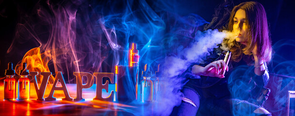 Woman vaper. Vaping gadgets on table. Girl smokes electronic cigarette. Lady vaper stands in smoke....