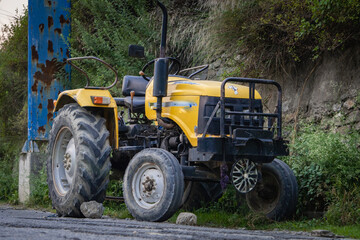Yellow tractor broken down on the side of a road in Himachal Pradesh, India.