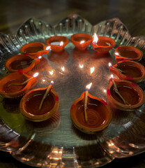 A close up shot of plate full of lit diyas on the occasion of Diwali