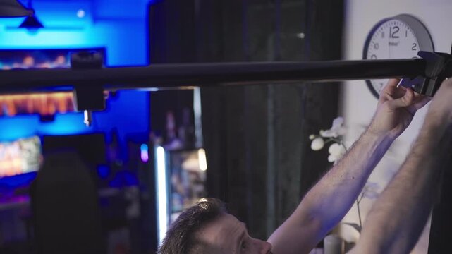 Person mounting clamps on pole between walls on video production set 4K