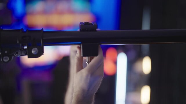 Person mounting clamps on pole between walls on video production set close-up 4K