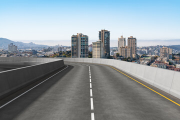 Obraz premium Elevated highway curve with city skyline in the background.