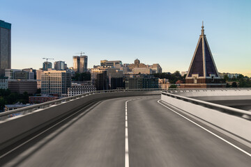 Elevated road with urban skyline in the background during sunset.