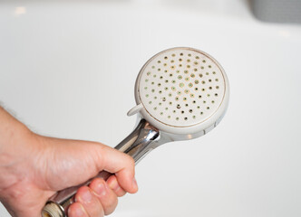 Old shower head. Limescale water stone buildup. Replacement and maintenance of plumbing fixtures....