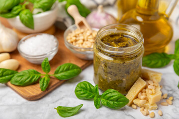 Pesto. Italian basil pesto sauce on a textured wooden background. Ingredient for pesto sauce: fresh basil, pine nuts, Parmesan cheese and olive oil. Space for text.Copy space.