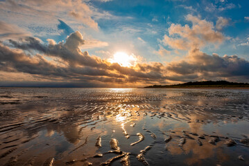 Sonnenuntergang mit dramatischem Wolkenhimmel über dem Watt der Nordseeinsel Föhr bei Ebbe