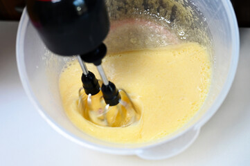 Breaking and whisking flour, eggs to prepare cake dough