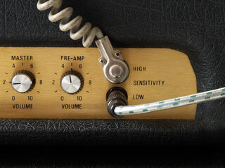 Closeup of part of an unbranded, generic vintage amplifier, with two instrument leads / cables /...