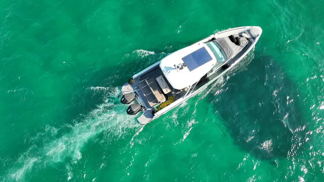 Aerial drone tracking video of small yacht cruising deep blue open ocean sea