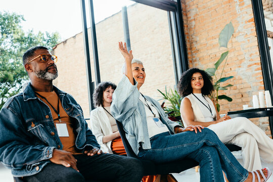 Diverse team brainstorming with a woman raising a question in an office meeting