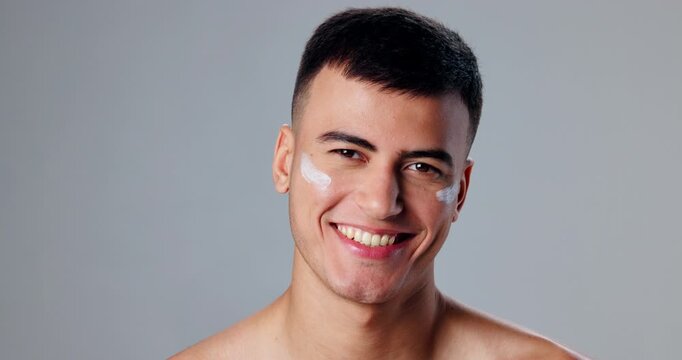 Face, smile and man with skincare, cream and dermatology on gray studio background. Portrait, person and model with confidence, grooming routine and treatment with smooth skin, wellness or lotion