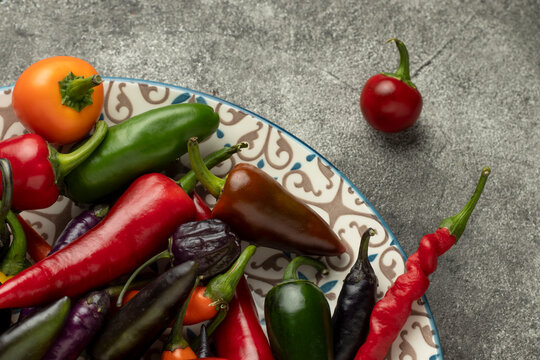 Mix of hot cayenne, jalapeno and buena mulata peppers on a plate. Top view.