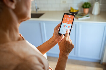 Close up of a middle aged woman holding smartphone with bank app