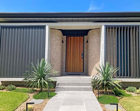 Front entrance of a new house with rounded brick walls and vertical louvers on the outside of the house
