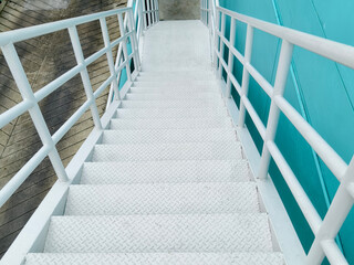 Metal stairs to blue building against sky and clouds