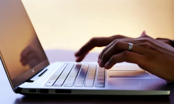 The Power of Productivity: Hands glide across a laptop keyboard, bathed in warm light, embodying focus and digital fluency in the modern workspace.