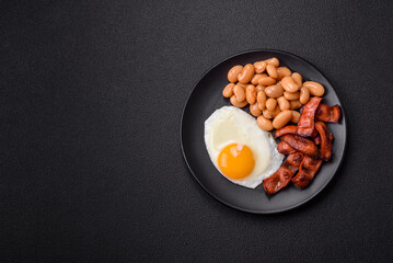 English breakfast with fried eggs, bacon, beans, tomatoes, spices and herbs