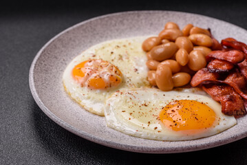 English breakfast with fried eggs, bacon, beans, tomatoes, spices and herbs