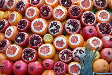 Fresh pomegranates cut in half on the counter in the shop Closeup of ripe pomegranates and grapefruits.