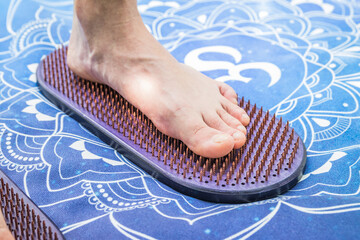 Feet on Nails Sandals on Mandala Yoga Mat for Healing and Relaxation Outdoors