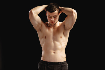 Fototapeta premium Sexy athletic man with naked torso posing showing his muscles on black background