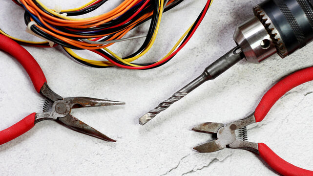Perforator, flat-nose pliers and colored wires. Repair tool kit, top view.