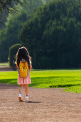 Little Girl with Yellow Backpack Walking Outdoors