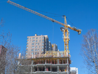 A tower construction crane lifts building materials to a height. The frame of a building under...
