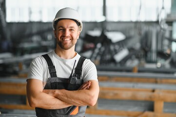 Portrait of a young worker in a hard hat at a large metalworking factory. Shiftman on the warehouse...