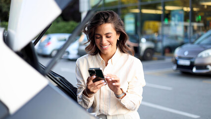 Beautiful, young woman using a smartphone on the parking of a shopping mall