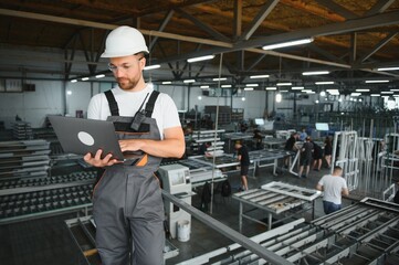 Smiling and happy employee. Portrait of industrial worker indoors in factory. Young technician with...
