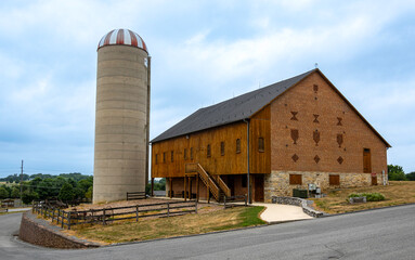 Restored 1881 Pennsylvania bank barn of wood, brick, and stone with large silo outdoors.