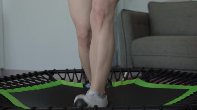 Woman jumping on a sports trampoline at home, engaging in a fun and energetic workout. Ideal for fitness and indoor exercise.