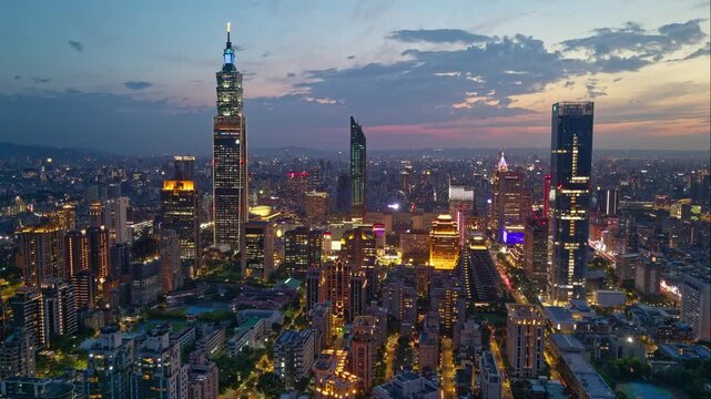Aerial hyperlapse at sunset above Downtown Taipei, the vibrant capital of Taiwan, with 101 Tower standing out amid skyscrapers in XinYi Commercial District and city lights dazzling under twilight sky