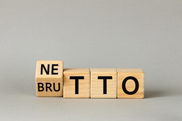 Netto and brutto. Net and gross symbol. Words on wooden blocks change net to gross. Financial concept, Beautiful gray background, copy space