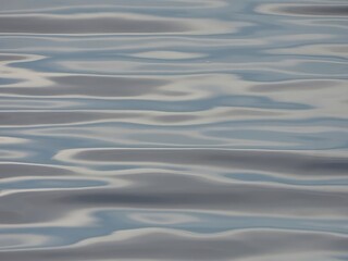 A calm blue water surface with gentle ripples and smooth reflections