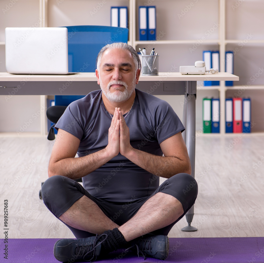 Canvas Prints White bearded old man employee doing exercises in the office