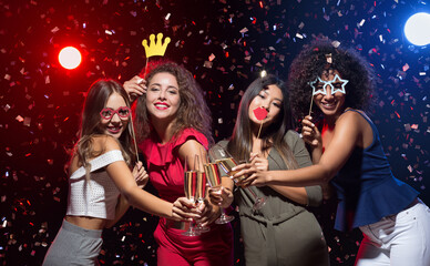 Fun at New Year party. Happy women celebrating and posing with photo props and champagne