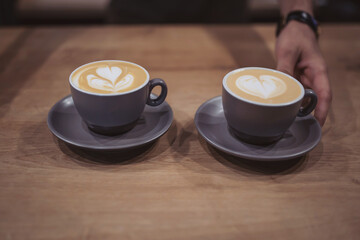 Close up of man serving coffee while standing in coffee shop. Focus on a cups of coffee on counter. cappuccino. Professional bartender serving the cup of freshly brewed coffee. 