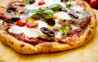 Hausgemachte Pizza mit Tomaten, Kalamata Oliven, Basilikum und Mozzarella