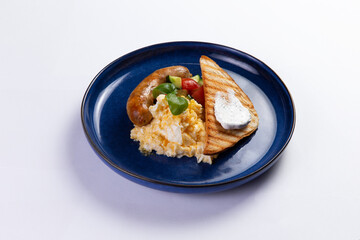 Scrambled eggs, sausage and toast in a plate on a white background.
