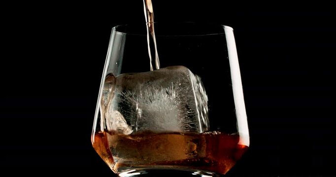 Glass, whiskey and ice with alcohol, pour and bourbon on black studio background. Empty, cold and smooth drink with refreshment, cognac and cube with scotch, luxury and liquor with closeup and brandy