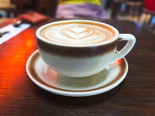 Detailed Rosette Latte Art in Ceramic Cup: Captivating Coffee Culture Photography on Wooden Surface.