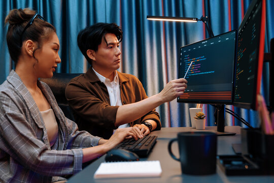 IT developers discussing with point to intelligent website development coder system running data online two screens information technology at neon light room at modern office. Infobahn.