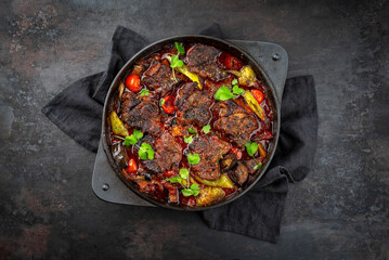 Traditional Greek braised lamb stew with vegetables and olives in a hearty meat sauce with red wine served as top view in a designer casserole with text space