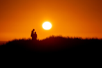 Sunset Silhouette of Couple Embracing on Hill