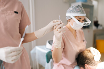 Closeup of male patient receiving hair loss treatment injections in scalp by trichologist....