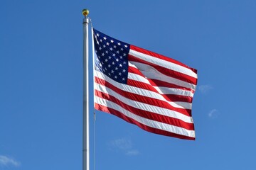 The american flag is waving in the wind on a clear blue sky day