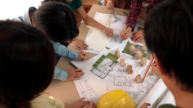 Architect and safety engineer discussion about building construction use blueprint on table with architectural document, measurement tool and wooden block scatter around at modern office. Delineation.