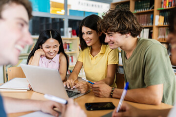 Young group of diverse students studying together using laptop at library. College multiracial people working on group assignment homework project at university.